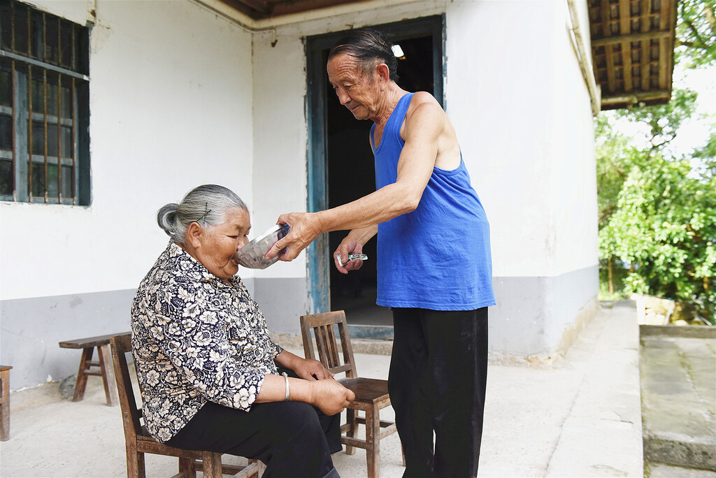 图3一早干活回来,曾启芳马上为妻子喂药